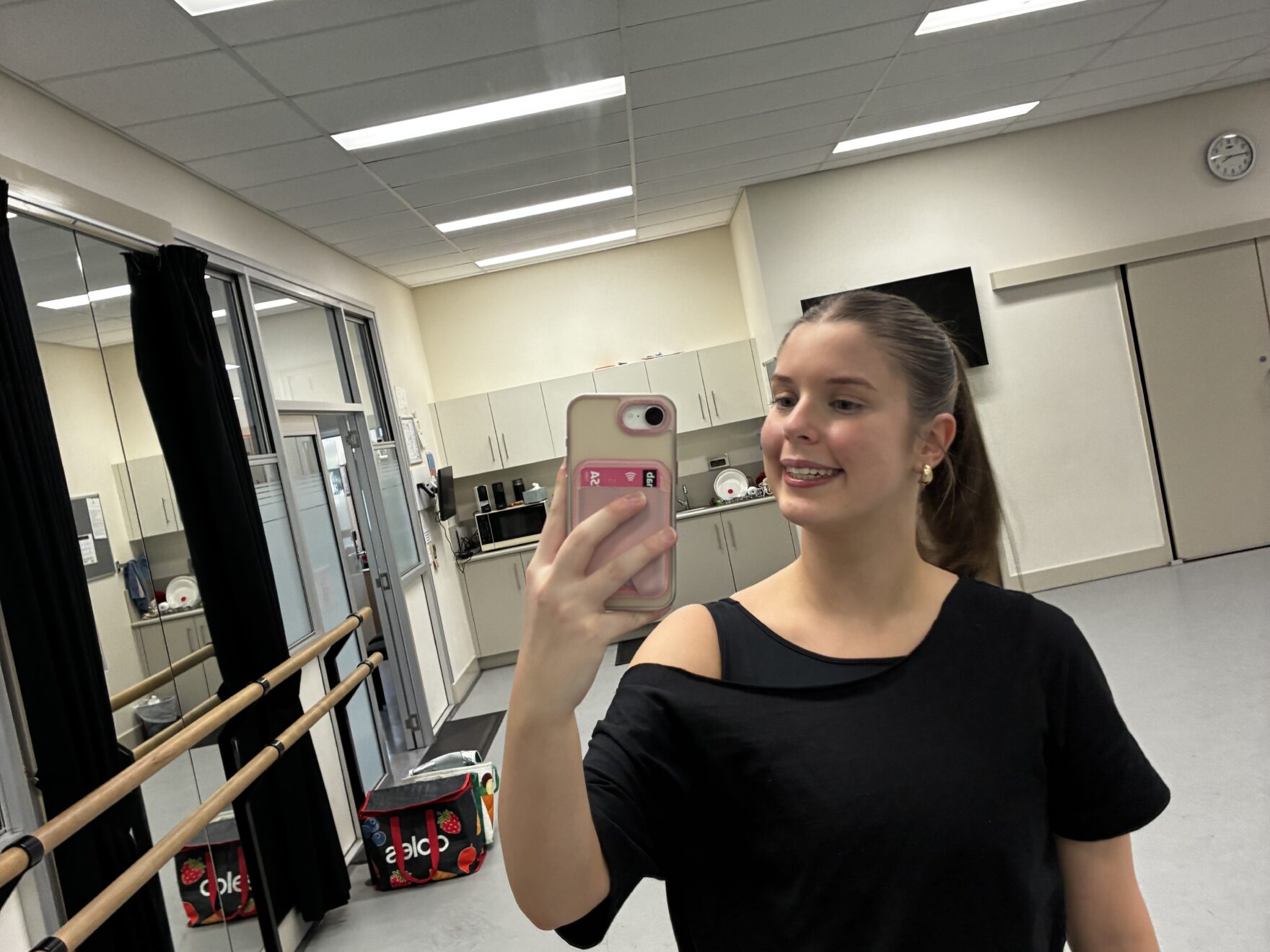 Ella takes a photo of her self smiling into a mirror.
