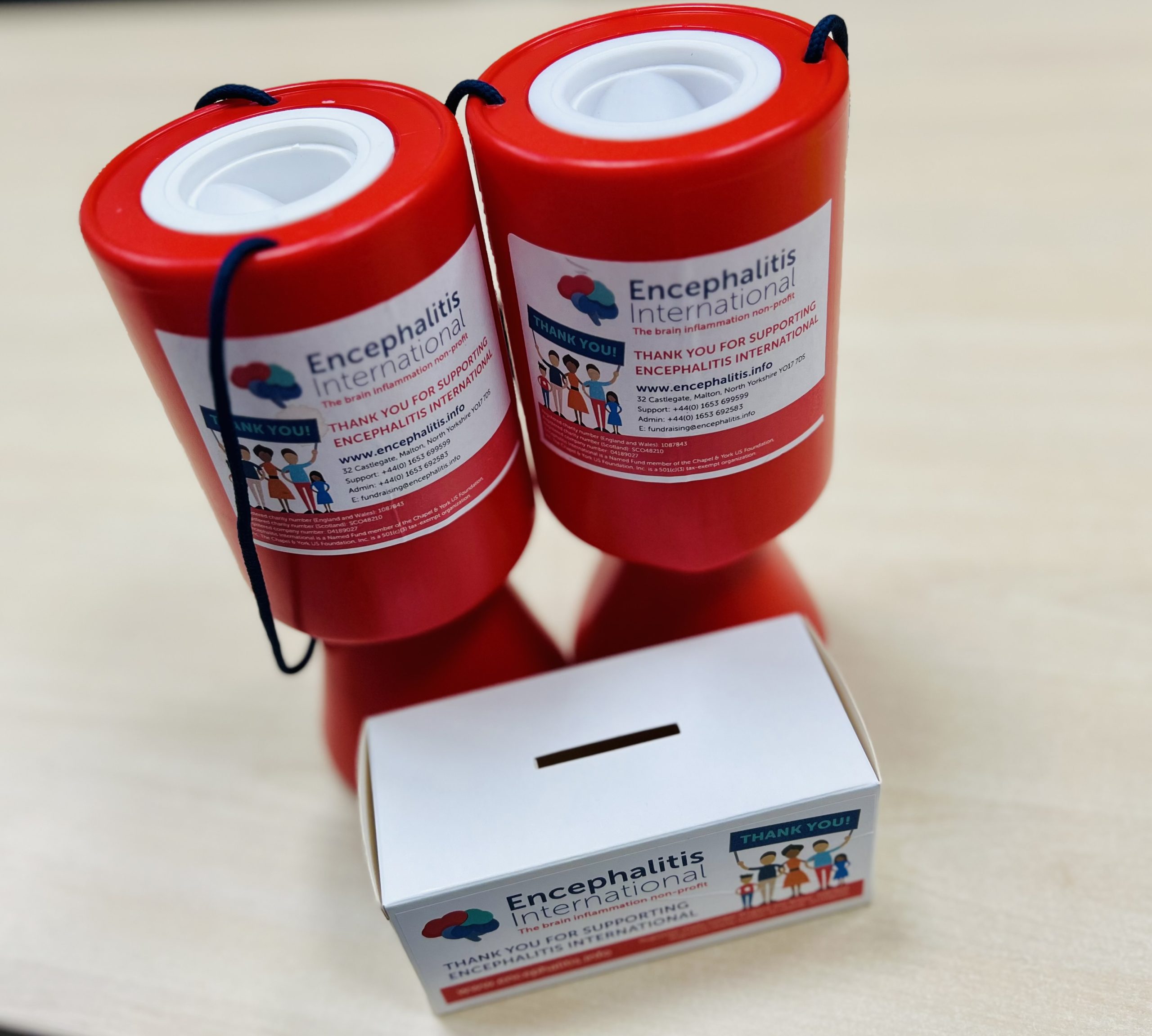 Fundraising resources: 2 red plastic Encephalitis International collection boxes and 1 white cardboard collection box.