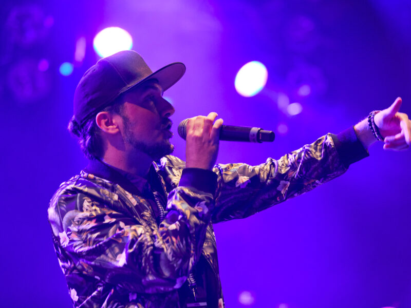 Man wearing a cap sings into a microphone
