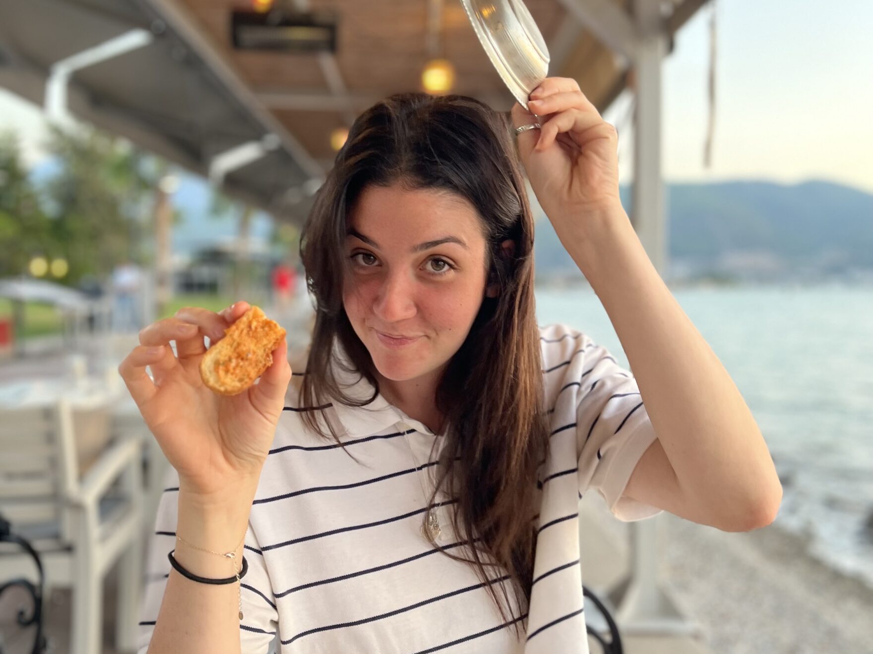 Woman holding a dish above her head and food in her hand.