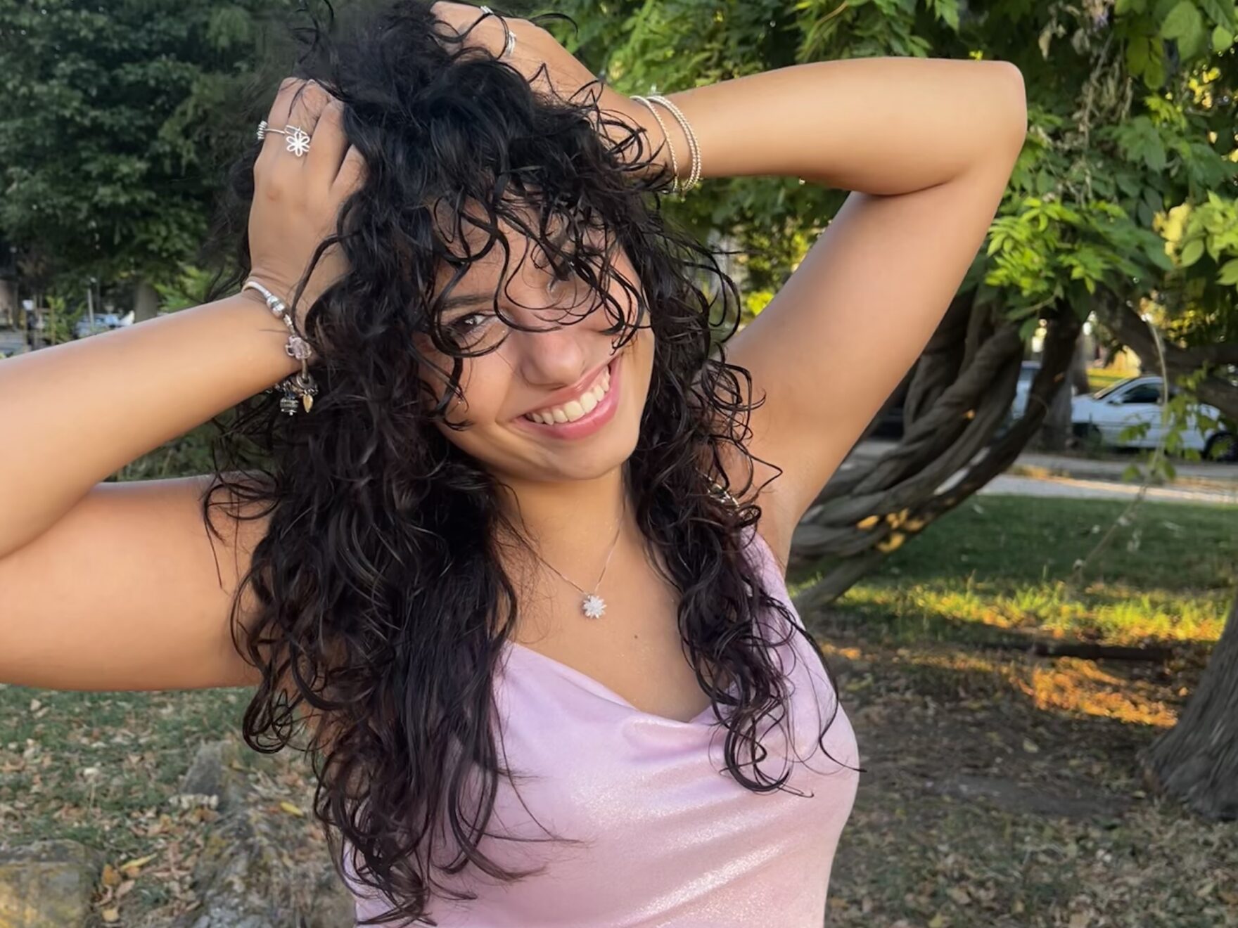 Woman with dark curly hair smiles at the camera