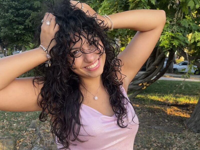 Woman with dark curly hair smiles at the camera