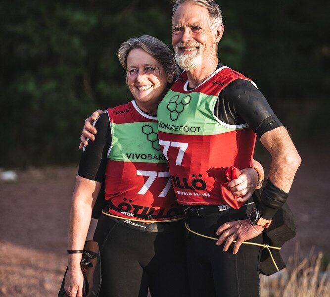 A man and woman stand next to each other in sports gear after completing a swimrun race.