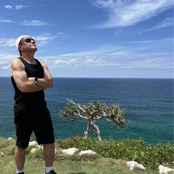 A man stands looking a clear blue sky.