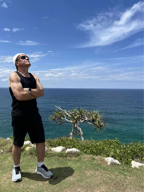 A man stands looking a clear blue sky.