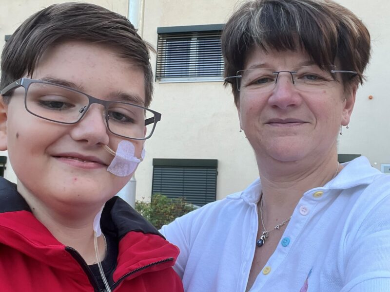Son and mother smile at the camera.