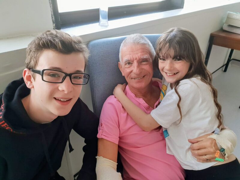 A man sits in the middle of his two grandchildren.