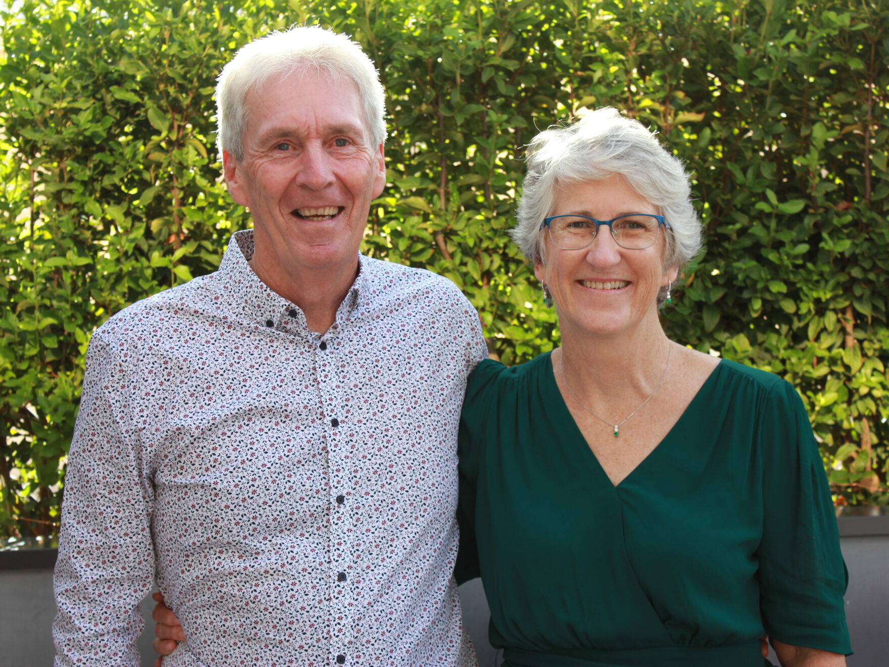 A couple stand smiling at the camera.
