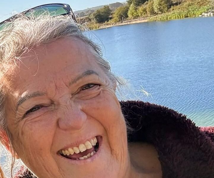 Gill smiles happily in front of a body of water.