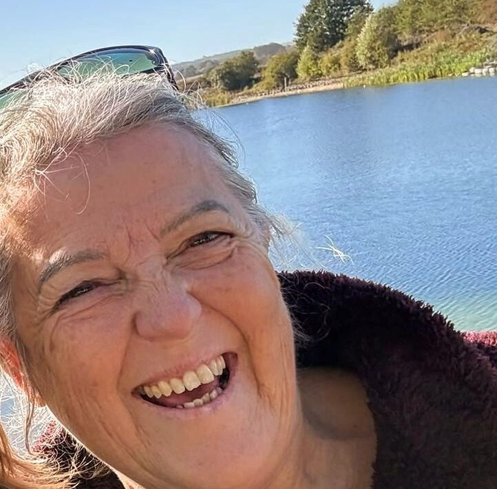 Gill smiles happily in front of a body of water.